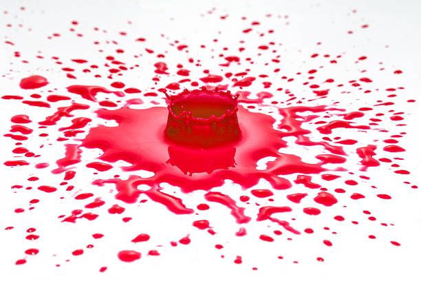 Impact of red color water drop on a white surface. Other red drops are in the vicinity of the impact.