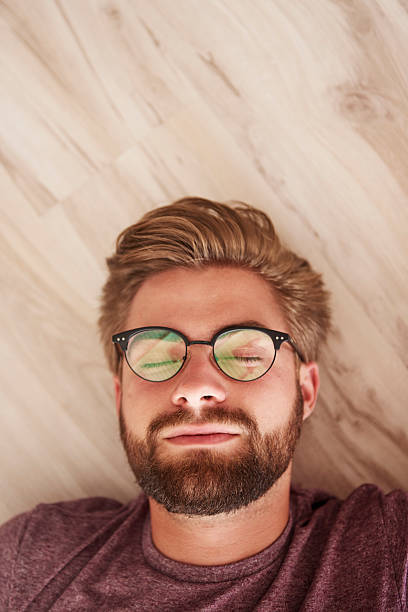 istock Man with glasses lying down on the floor 610421582