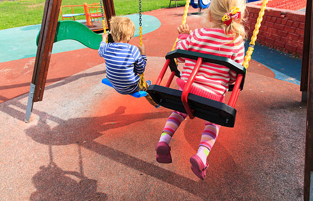 istock kids having fun on swings at playground 610422368