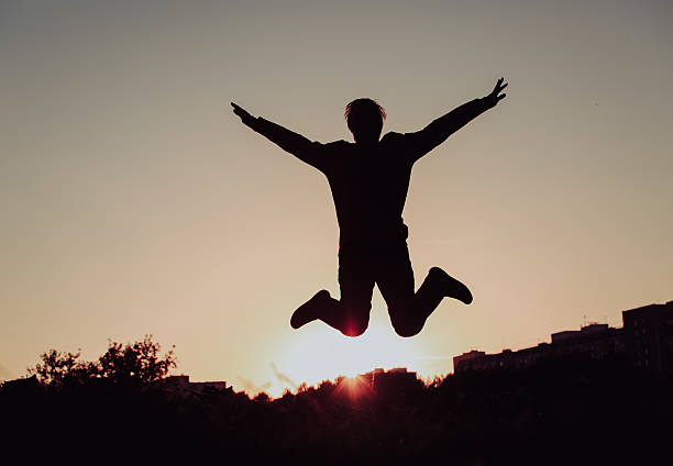 istock Silhouette of man jumping at sunset sky, happiness 610424054
