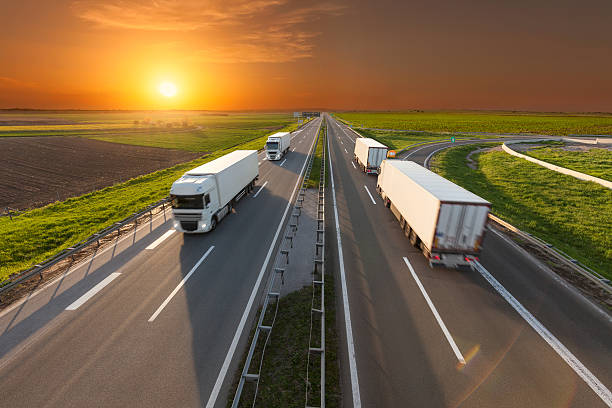 istock Four white trucks on highway at idyllic sunset 610425420