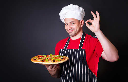Portrait of happy attractive cook with a pizza in his hands