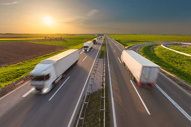 istock Modern white trucks on highway at idyllic sunset 610425644
