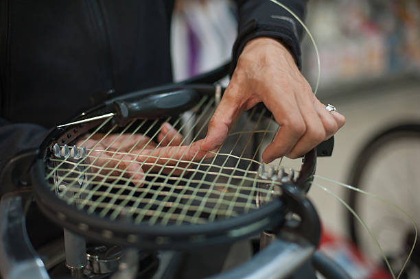 Close up of tennis stringer hands doing racket stringing Stringing Machine. Close up of tennis stringer hands doing racket stringing in his workshop musical instrument string stock pictures, royalty-free photos & images