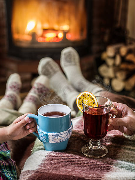 Relaxing near fireplace with a cup of hot drink. Warming and relaxing near fireplace. Woman feet near the cup of hot drink in front of fire. heat home interior comfortable human foot stock pictures, royalty-free photos & images