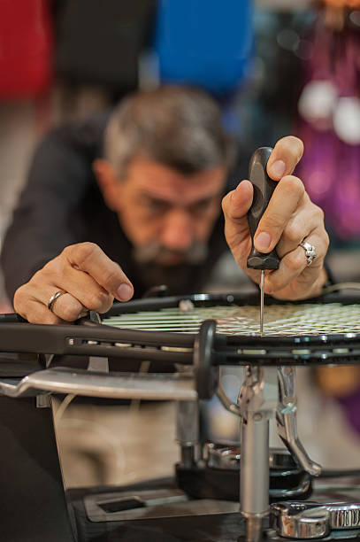 stringer de tennis tenant un poinçon et faisant du stringing de raquette - racket tennis stringing restringing photos et images de collection