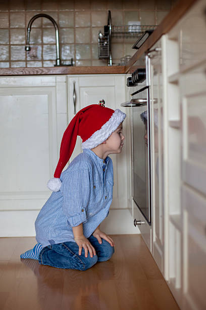 istock Curious little boy, watching ginger bread cookies in the oven 610429556