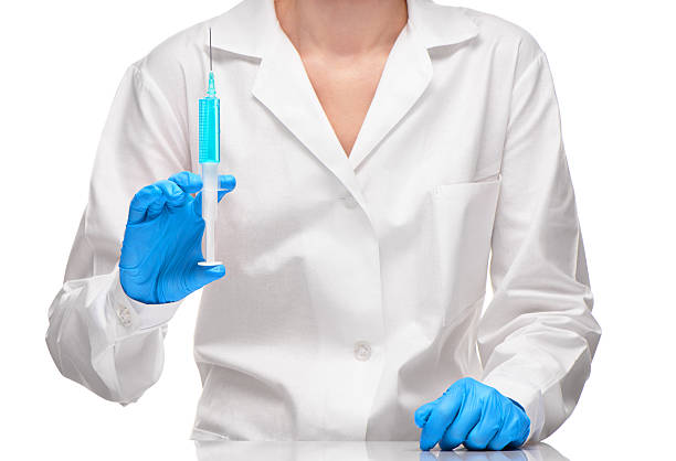 médecin en robe blanche et gants bleus tenant la seringue - surgical needle syringe prick injecting photos et images de collection