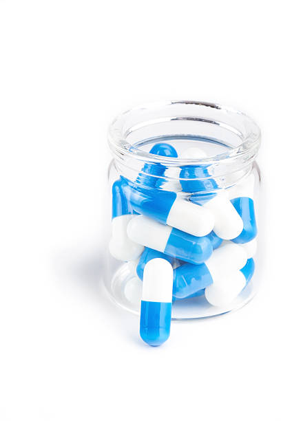 Blue white capsules in glass container on white stock photo