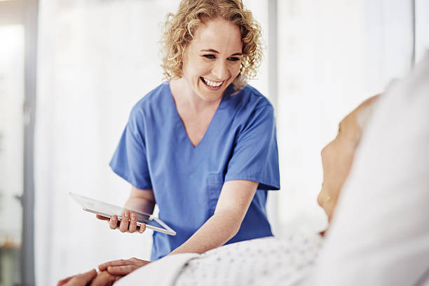 You'll be outta here in no time Shot of a female carer talking to her recovering male patient old woman smiling tablet stock pictures, royalty-free photos & images