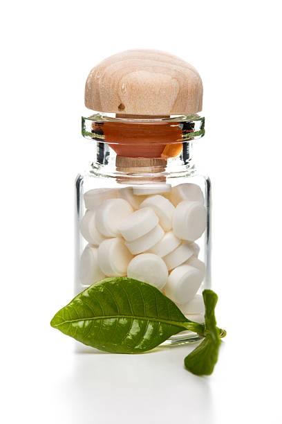 White pills in glass container with wooden top stock photo