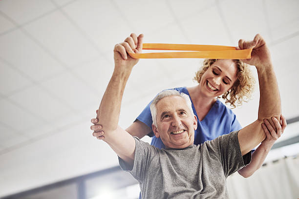 She'll have him rehabilitated in no time Shot of a female physician working with a senior patient in a nursing home recovery stock pictures, royalty-free photos & images