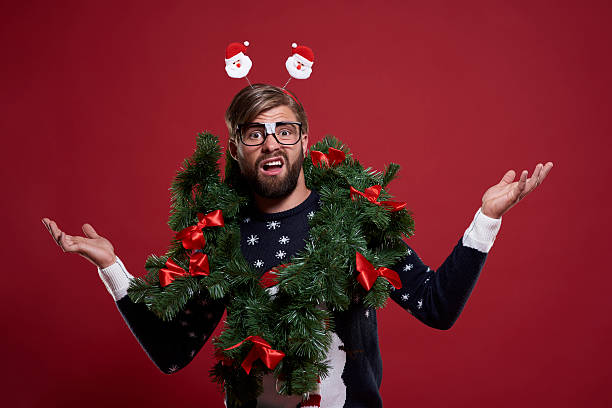 Man in embarrassing Christmas garland Man in embarrassing Christmas garland christmas nerd sweater cardigan stock pictures, royalty-free photos & images