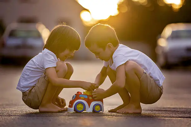 Photo of Two sweet children, boy brothers, playing with car toys