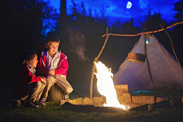 Two sweet boys, sitting around the campfire after sunset, listening scary stories