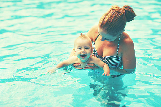 istock mother teaching baby swimming pool 610442344