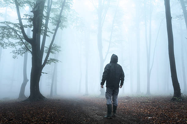 istock Dark horror man in creepy foggy forest 610442704