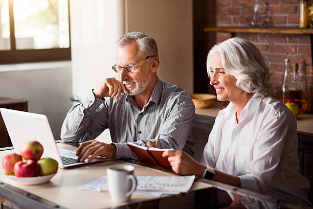 istock Happy senior couple using laptop at the kitchen 610443540