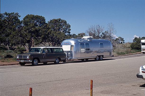 California, USA, June 17, 1977. Airstream Trailer on a Highway in California, 1977. SUV with an Airstream trailer on a Highway in California. Airstream Caravans are manufactured in USA since 1931 until today. Unmistakable is the streamlined design aluminum housing of the trailer. 