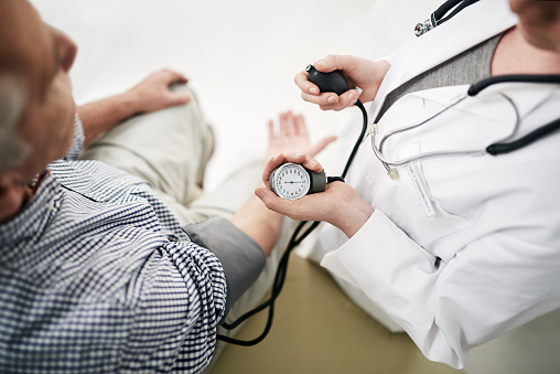 Shot of a doctor checking a senior patient's blood pressure in her office