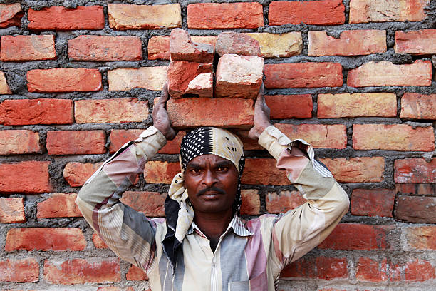 main-d’œuvre transportant des briques sur la tête sur le chantier de construction - porter sur la tête photos et images de collection