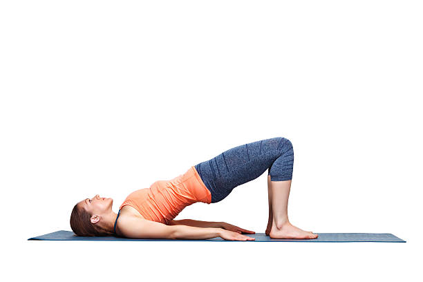Beautiful sporty fit yogi girl practices yoga asana setu bandhasana Beautiful sporty fit yogini woman practices yoga asana setu bandhasana - bridge pose beginner variation in studio isolated on white setu bandhasana stock pictures, royalty-free photos & images