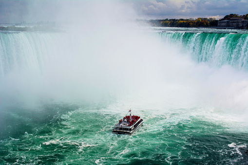 Niagara Falls, Ontario, Canada, 16 October, 2014: The iconic Maid of the Mist passes along the Niagara River into the basin of Horseshoe Falls.