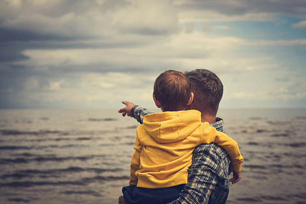 istock Father and son enjoying the view at the beach 610542590