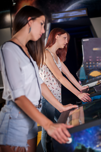 Young woman playing on the pinball machine in game room