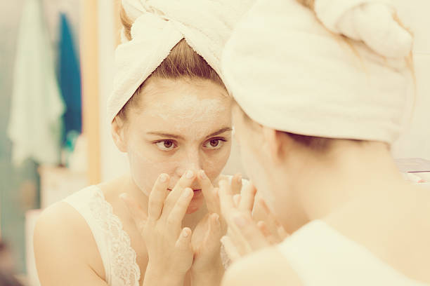 istock Woman applying mask cream on face in bathroom 610544906