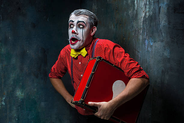 Terrible crazy clown and Halloween theme Terrible clown and Halloween theme: Crazy red clown with suitcase on a dark background face paint halloween adult men stock pictures, royalty-free photos & images