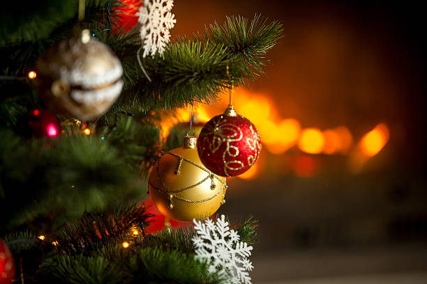 istock Golden baubles on Christmas tree on background of burning fireplace 610545492