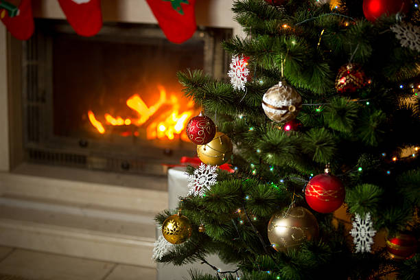 istock Decorated Christmas tree in front of burning fireplace at house. 610545622