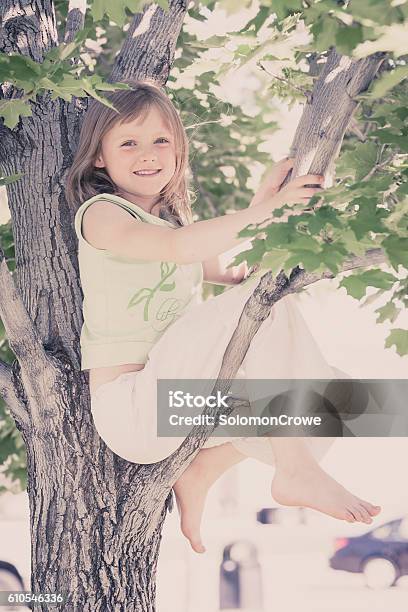 Young Blonde Girl In Garden Climbing Tree Stock Photo - Download Image Now - Activity, Blond Hair, Branch - Plant Part