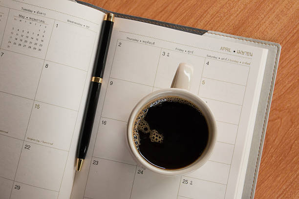 istock Cup of coffee and pen on notebook with calendar planner 610548726