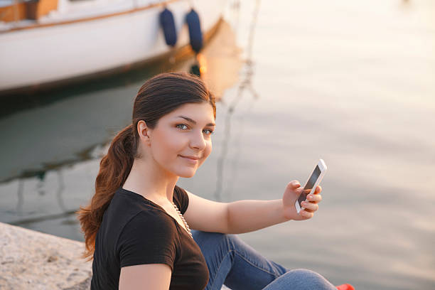 istock Young women holding using smartphone  Casual lifestyles Sunset at sea 610549934