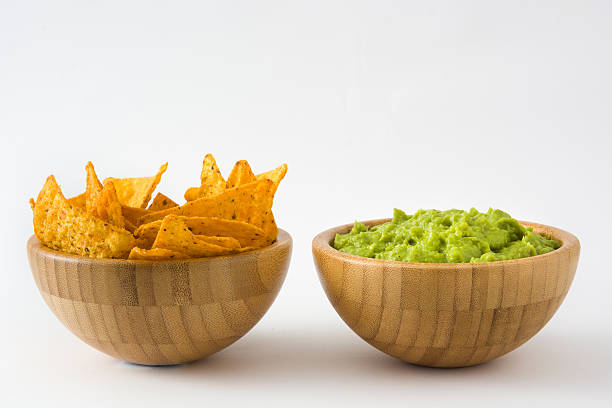 Guacamole in a wooden bowl Guacamole in a wooden bowl and nachos isolated on white background guacamole stock pictures, royalty-free photos & images