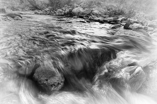Beautiful Reshi River water flowing through stones and rocks at dawn, Sikkim, India. Reshi is one of the most famous rivers of Sikkim flowing through the state and serving water to many local people. Black and white image.