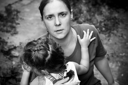 A woman holds a child, trying to calm him down. The child is three years.