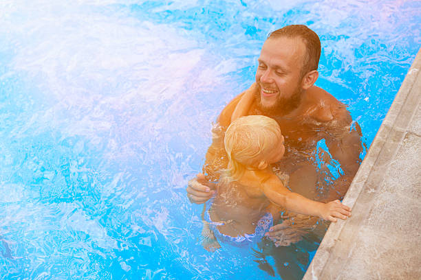 istock Father and son playing in the pool 610556022
