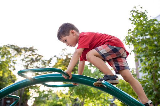 Little boy climbing a play structure at the playground