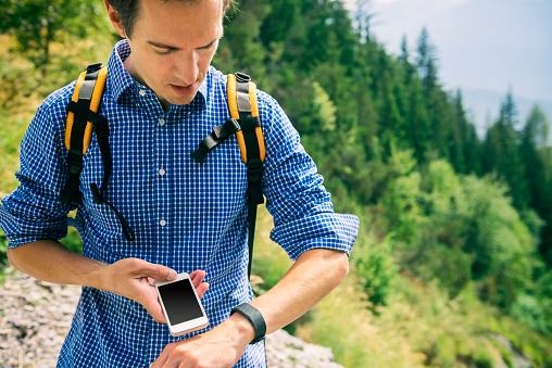 Attractive hiker in the swiss/european mountains wearing a backpack as well as an activity tracker