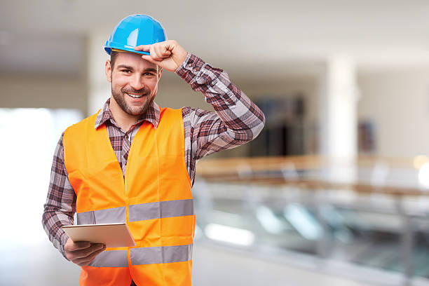 trabajador sonriente con tableta digital - blue construction built structure indoors fotografías e imágenes de stock