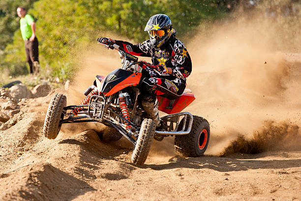 Quad bike in dust cloud, sand quarry on background. ATV Rider in the action.