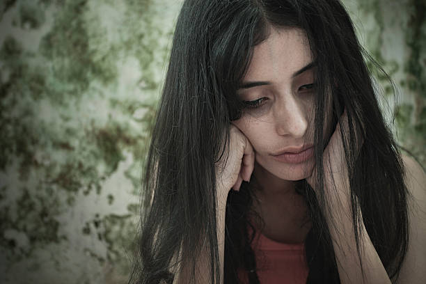 istock Sad girl thinking, looking down while sitting near dirty wall. 610563820