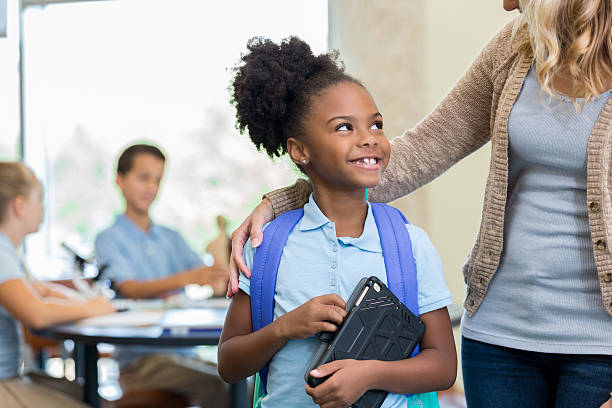 istock Cute African American schoolgirl talks with teacher before class 610564390