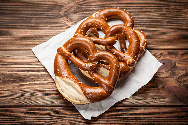 bretzels sur tableau en bois - pretzel german culture food salt photos et images de collection