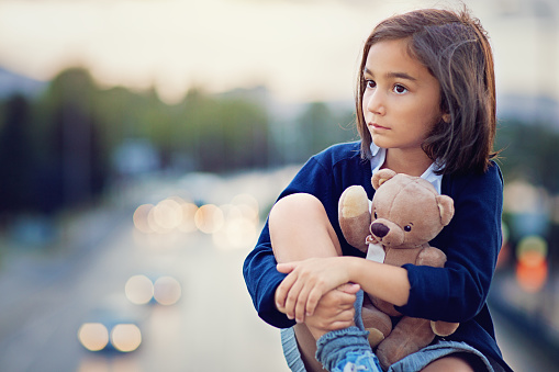 Little girl is standing sad on the bridge