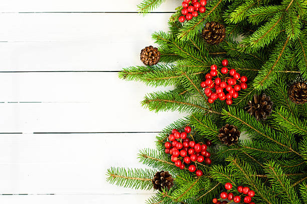 istock Fir tree branches decorated with red berries on  wooden  table 610565398