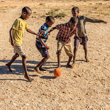 Barefoot African children  from Samburu tribe playing football in the village, East Africa, Kenya, East Africa. Samburu tribe is one of the biggest tribes of north-central Kenya, and they are related to the Maasai.